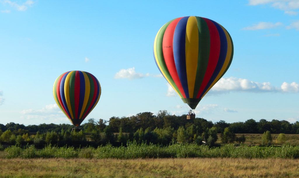 2 montgolfières décollent d'un champs