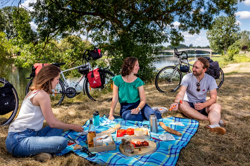 3 personnes autour d'un pique-nique avec vélos à côté