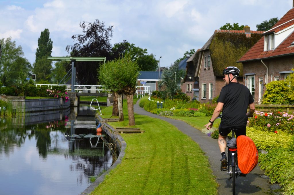 Cycliste dans petite ville hollandaise à côté d'un canal