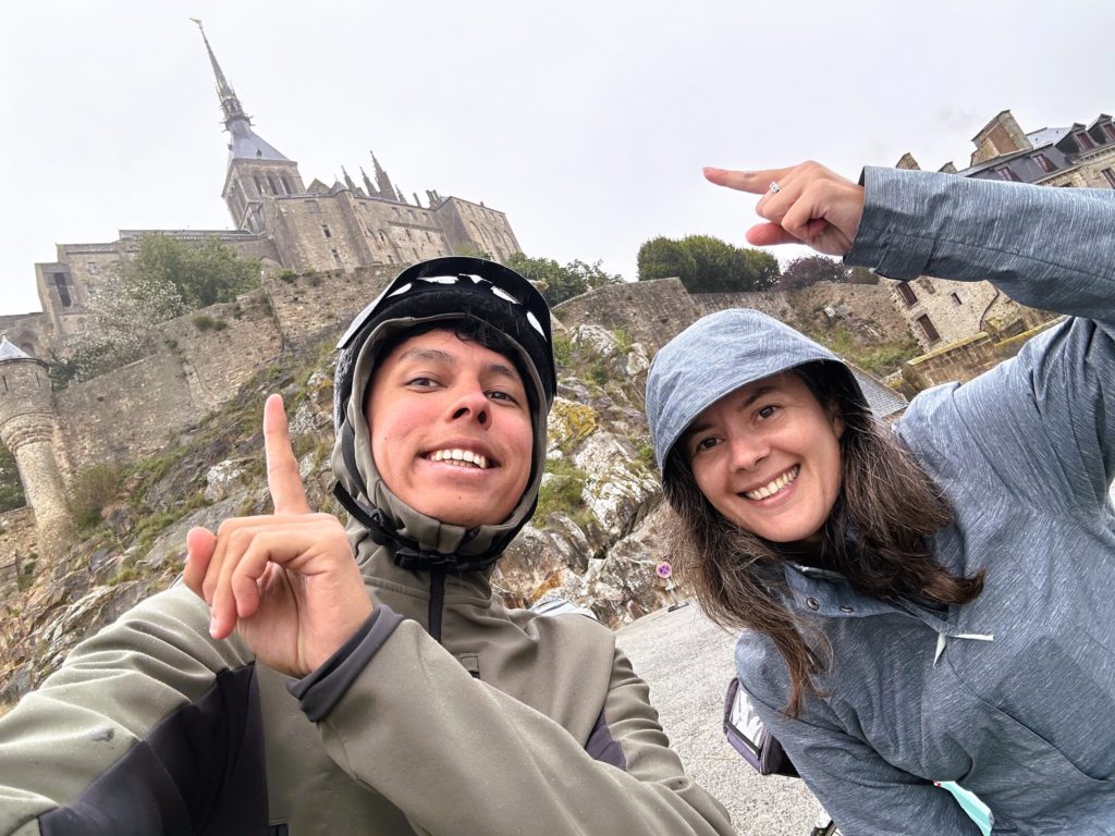 2 cyclistes souriants avec en arrière-plan le Mont-Saint-Michel